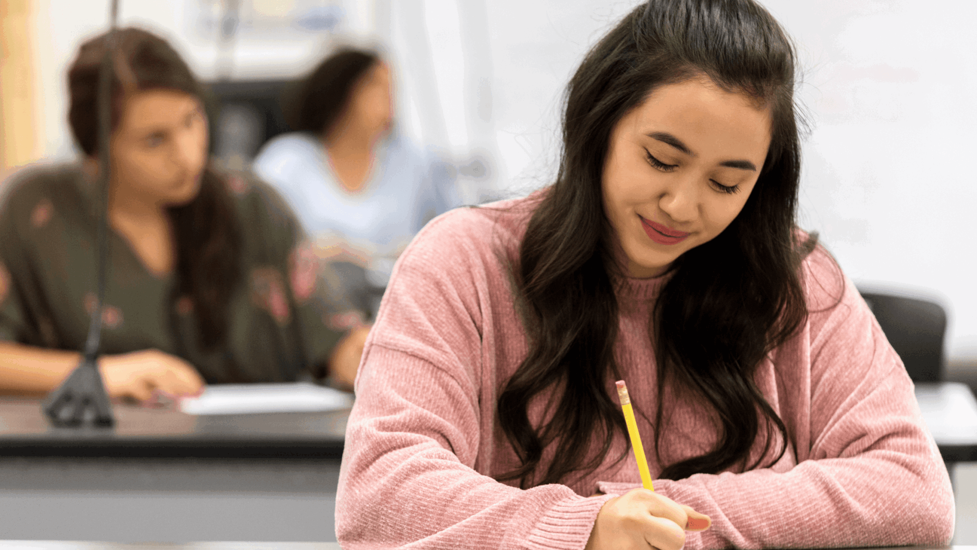 Female student in [ink jumper undertaking a test